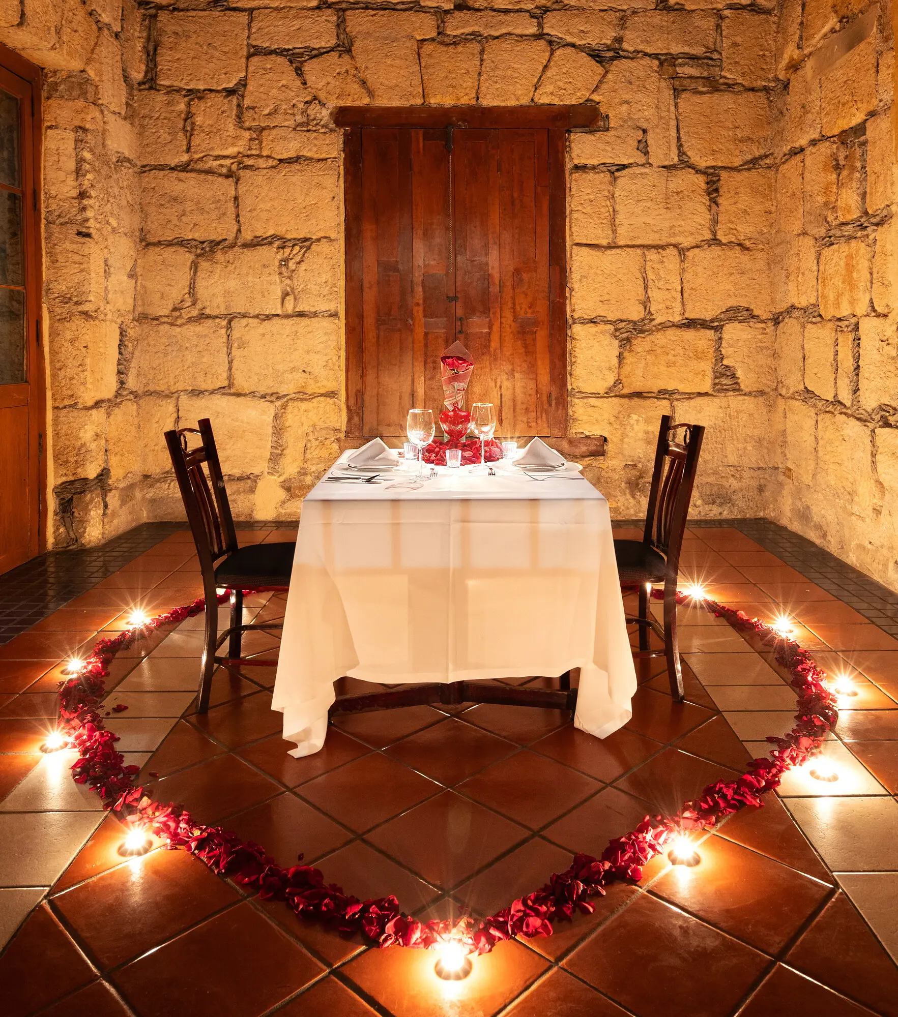 La mesa para dos en el Salón del Jefe, con el corazón de pétalos y velas en el piso